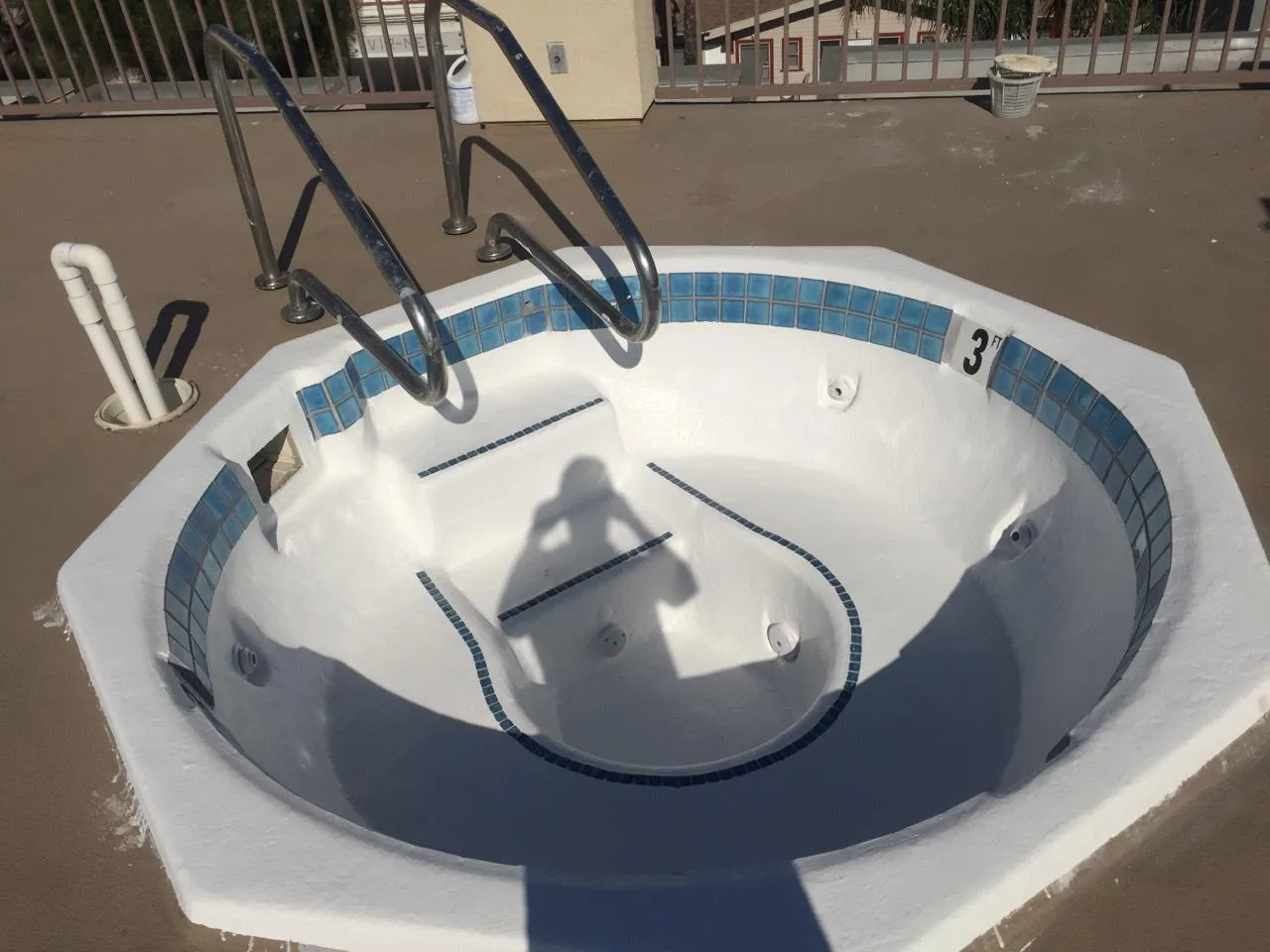 After: empty octagonal commercial spa with a renewed white interior finish and blue waterline tile, before filling.