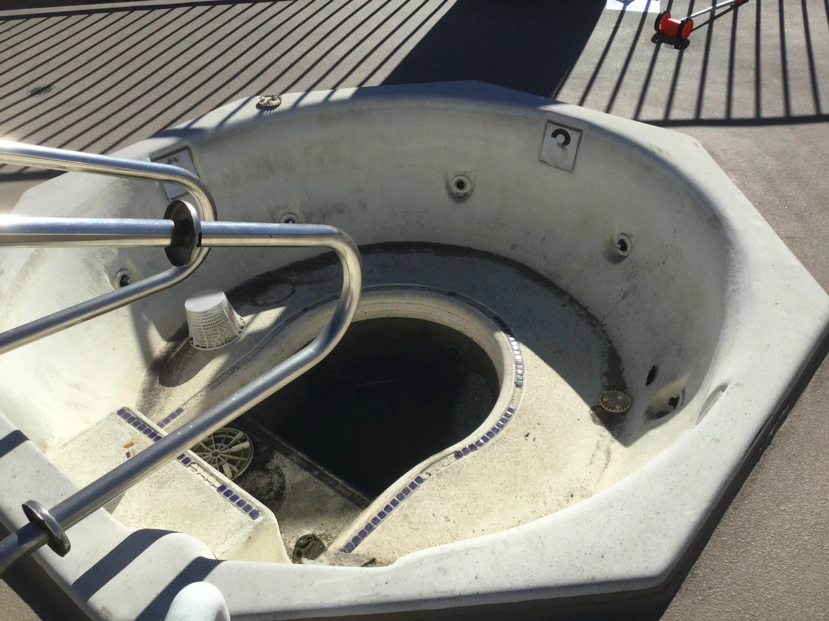 Before: drained octagonal commercial spa with a worn, stained interior and old tile trim.