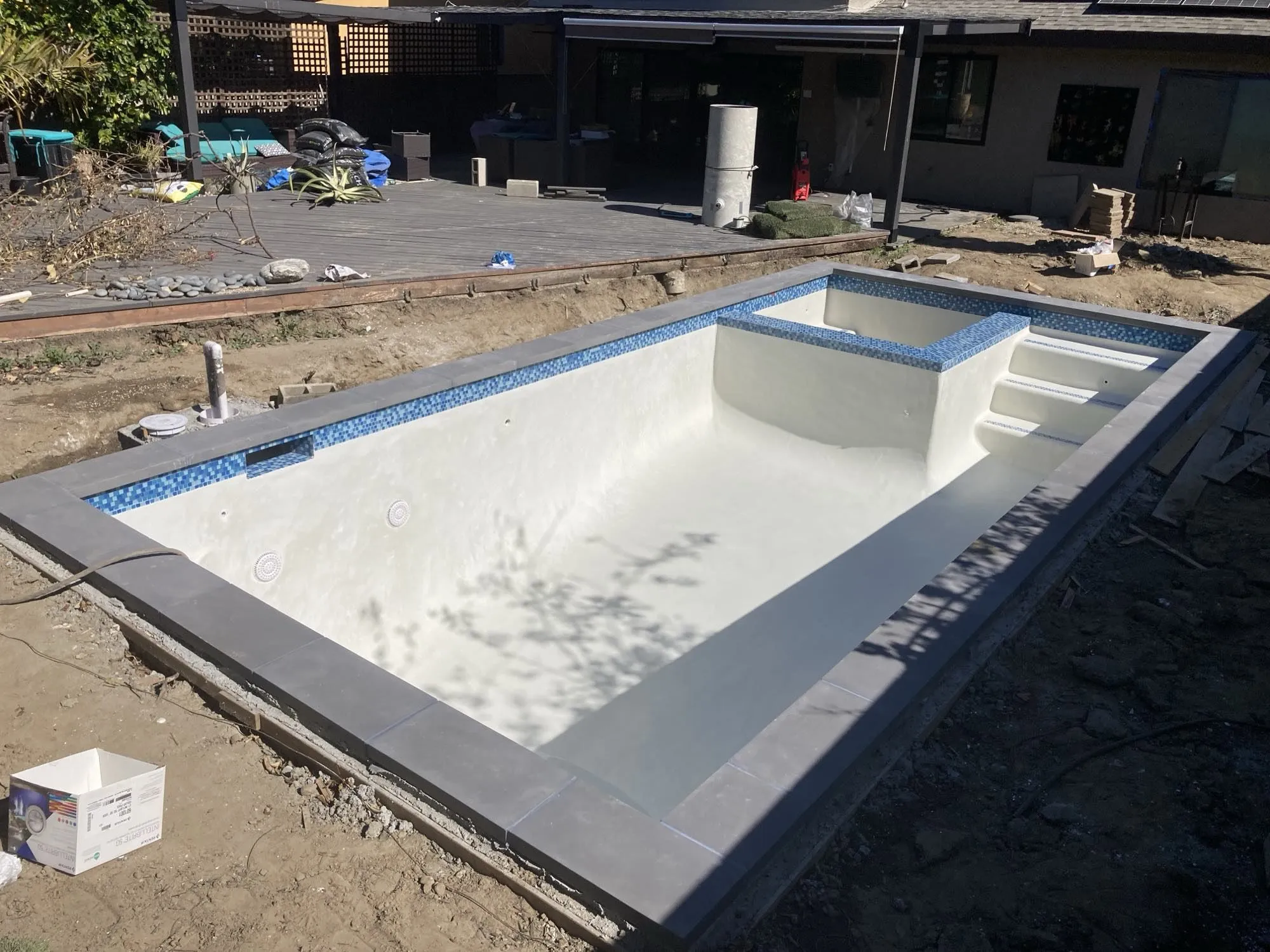 Freshly plastered pool interior with raised spa and tile spillway, not yet filled
