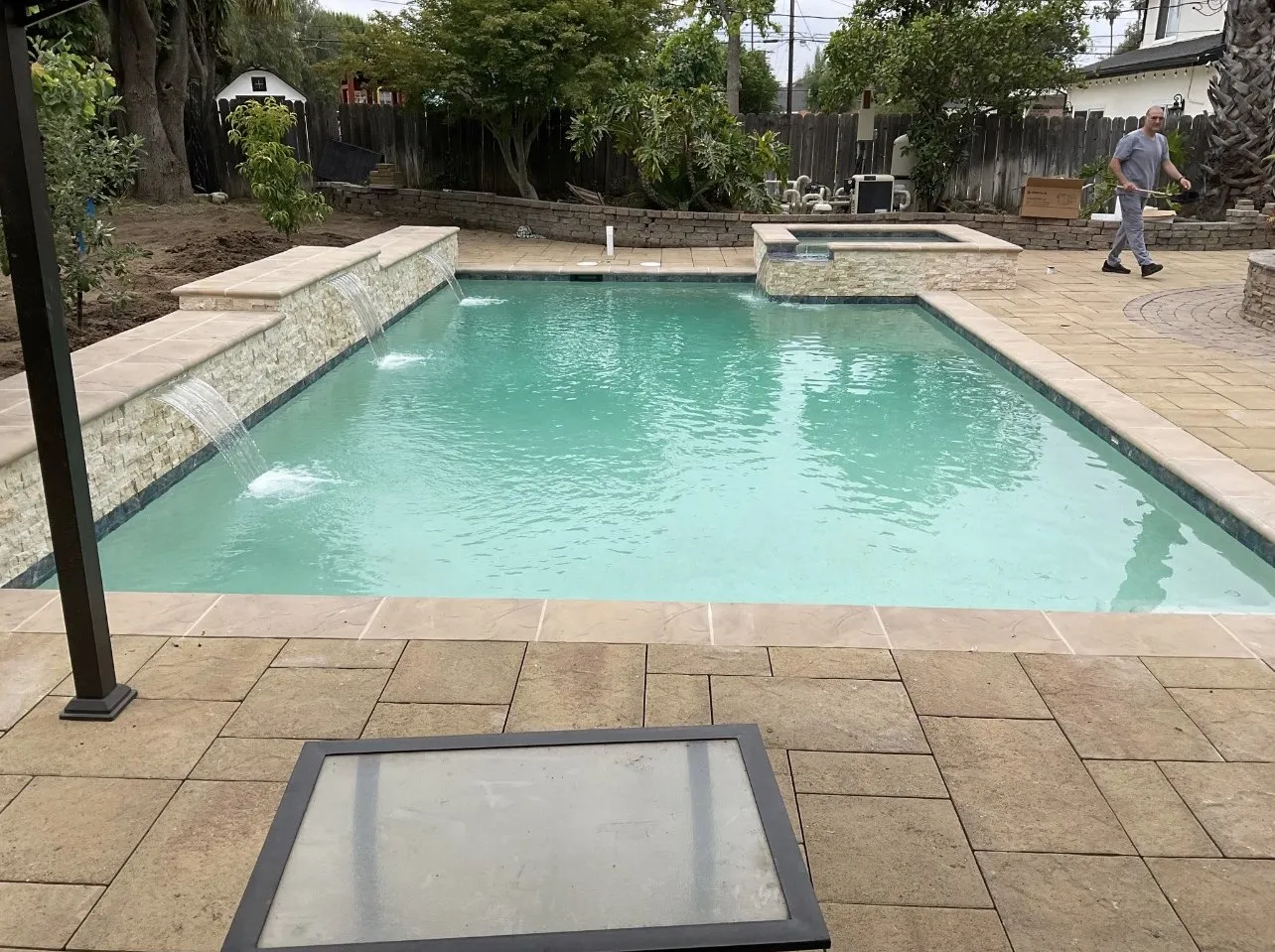 After: Finished pool with a natural-stone accent wall and three tiled water scuppers.