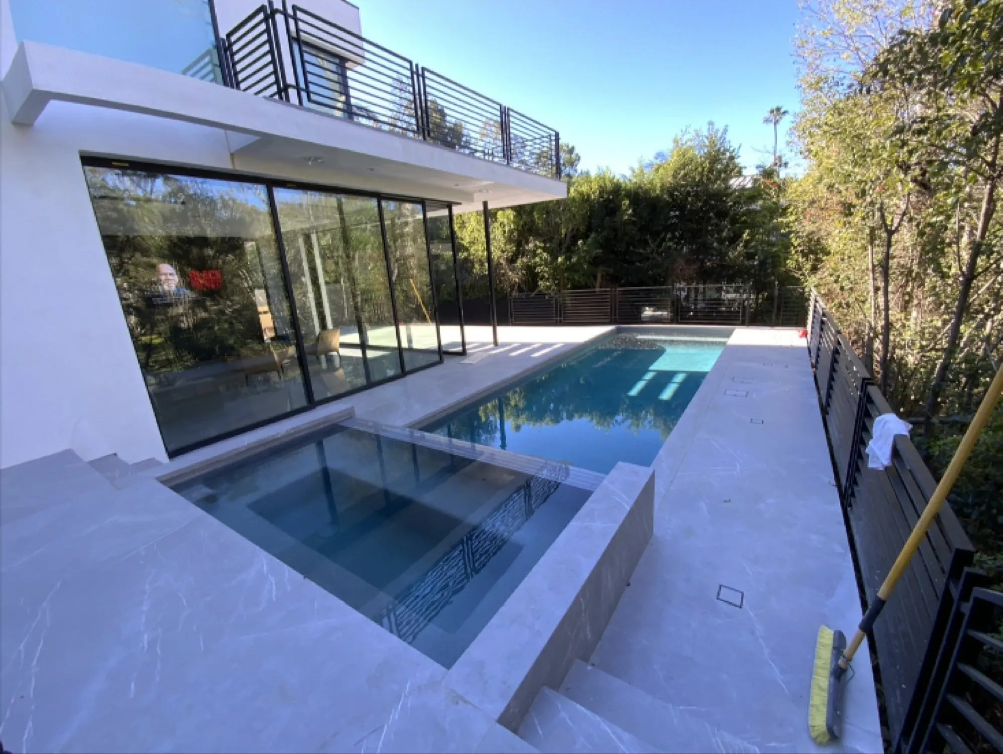 After: finished elevated modern pool and spa beneath a glass balcony