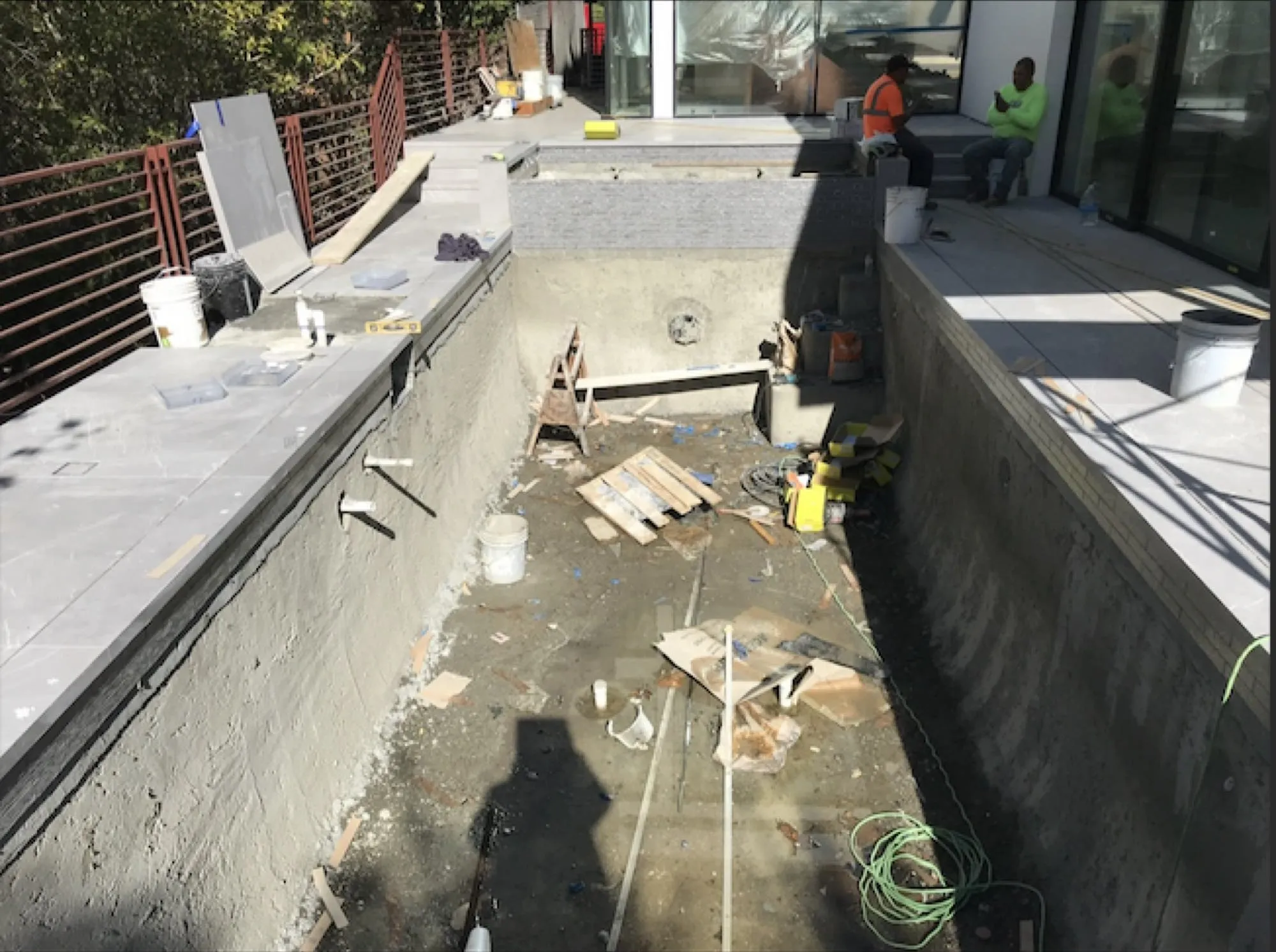 Before: deck under construction in front of a modern glass-walled house