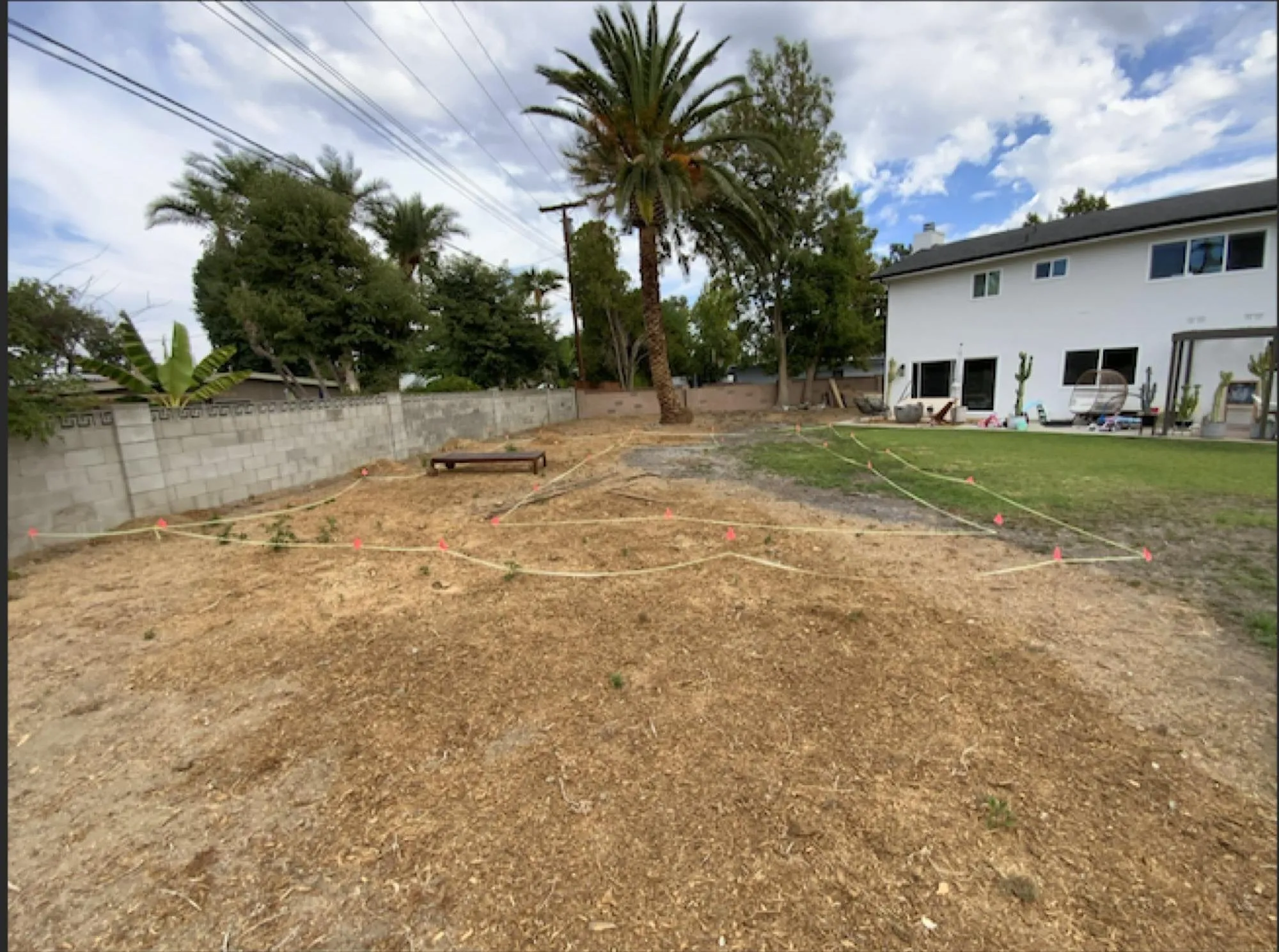 Before: bare dirt lot staked out with string lines marking the future pool shape