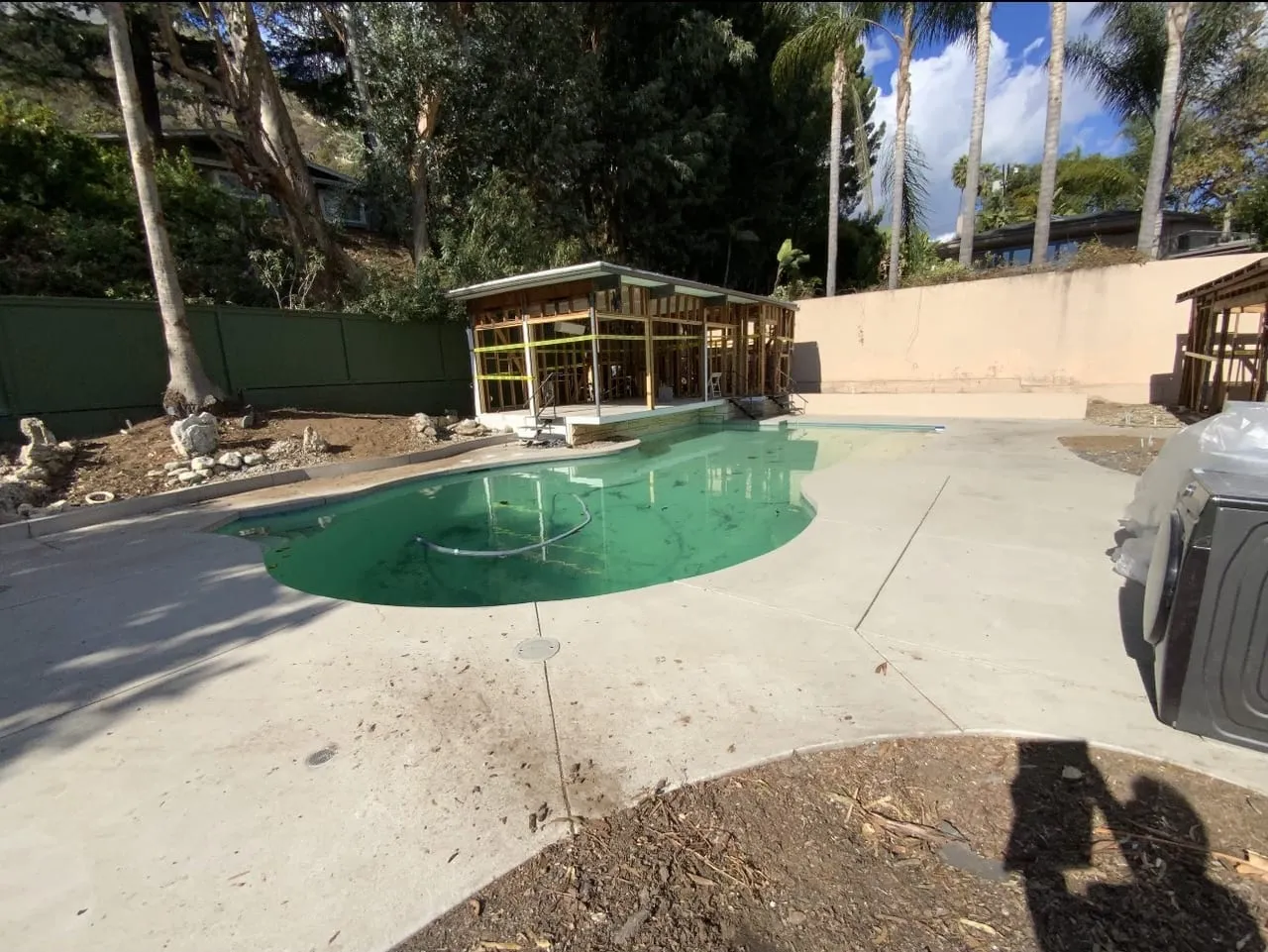 Before: Pool full of green water beside an unfinished cabana structure.