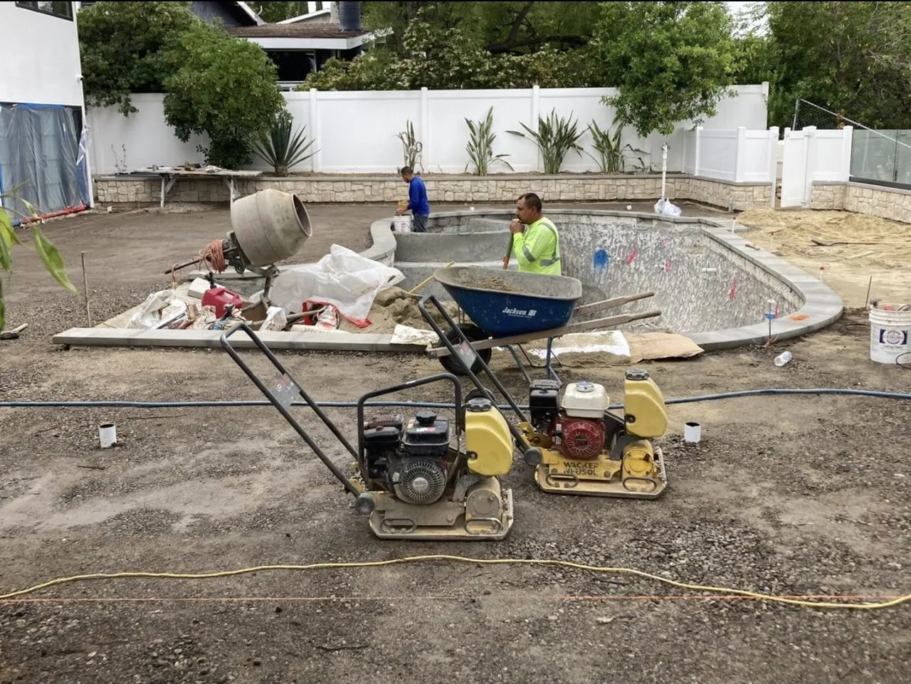 Before: Pool shell mid-construction with equipment and bare dirt around it.